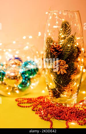 Coni in vaso di vetro e ghirlande sul tavolo Foto Stock