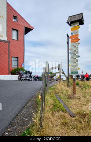 Numerosi cartelli di direzione sono abbelliti su un palo di fronte alla torre panoramica di Komari vizka sulla collina di Komari hurka, repubblica Ceca. Foto Stock