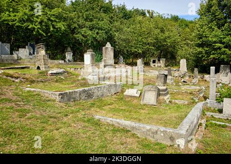 Terreno di sepoltura sovra e desolato nel cimitero fatiscente e abbandonato di Horni Krupka vicino alla torre panoramica di Komari vizka, Repubblica Ceca. Foto Stock