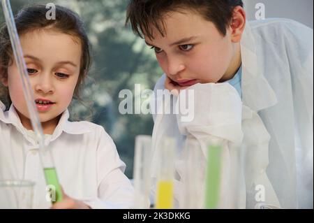 Adorabili bambini caucasici, ragazzi e ragazze, studenti intelligenti in classe scientifica sperimentando con liquidi. Chimica di apprendimento Foto Stock