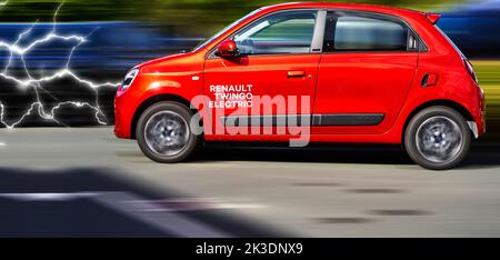 Renault Twingo elettrico, vista laterale di una piccola auto elettrica rossa contro sfondo dinamico sfocato con lampi dalla parte anteriore, posizione del veicolo Hannover, GE Foto Stock