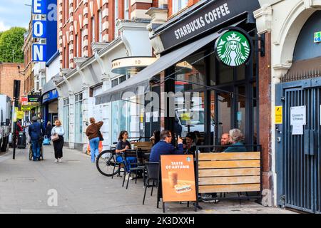 Persone sedute fuori dallo Starbucks Coffee Shop a Parkway, Camden Town, Londra, Regno Unito Foto Stock