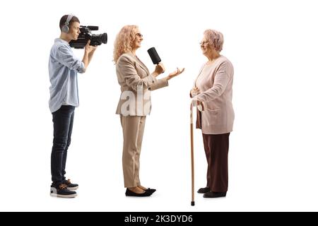 Giornalista di sesso femminile intervistando una donna anziana e un cineoperatore che ha girato isolato su sfondo bianco Foto Stock