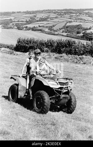 Contadino e due ragazzi in quad, High Bickington, North Devon, Inghilterra, Regno Unito. Foto Stock