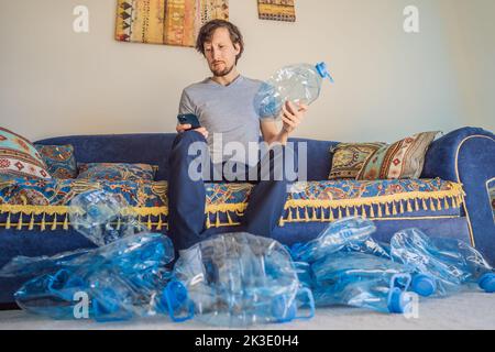 Il giovane uomo caucasico ha tra bottiglie di plastica vuote da riciclare con triste espressione Foto Stock