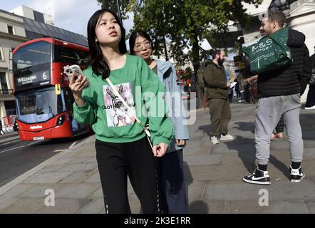 Londra, Inghilterra, Regno Unito. Giovane donna asiatica con un telefono cellulare nello Strand Foto Stock