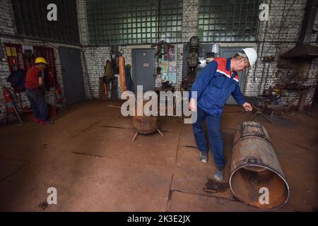 Lviv, Ucraina. 2nd Set, 2022. Un uomo guarda ad una stufa di metallo speciale pronta-fatta per riscaldare i seminterrati di case e rifugi, che saranno installati a Lviv a causa dell'invasione militare russa dell'Ucraina. Le imprese comunali di Lviv fabbricano stufe metalliche speciali che possono essere usate per riscaldare rifugi e seminterrati di case. A causa della minaccia di distruzione di infrastrutture critiche da parte di bombe russe, Lviv potrebbe essere senza riscaldamento in inverno. Queste stufe sono fatte per provvedere persone con calore. Per ottenere calore da loro, dovete bruciare legno in loro. La città progetta di fabbricare e installare circa Foto Stock