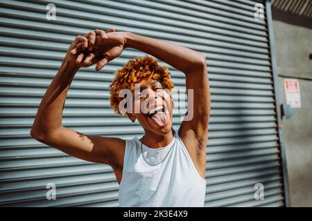 Adolescente afroamericano con glitter sul suo viso che balla per strada Foto Stock