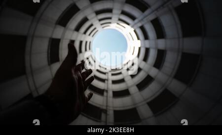 Tubo di ingresso a spirale di un garage in cemento con vista sul cielo blu e sulle nuvole bianche. Riprese grandangolari dal basso verso l'alto Foto Stock