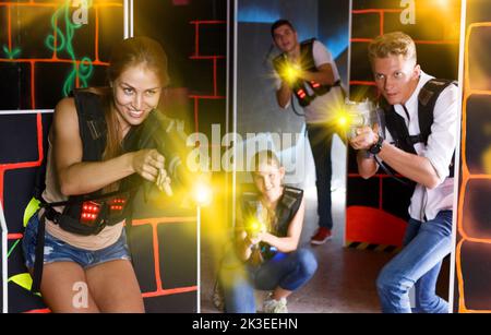 Amici eccitati in giubbotti e con pistole laser che giocano emotione Foto Stock