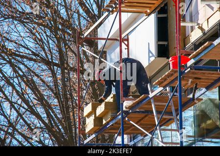Dnipro, Ucraina - 02.15.2022: Builder installa una piastra isolante da per il risparmio energetico. Il concetto di risparmio di calore durante la crisi. Foto Stock