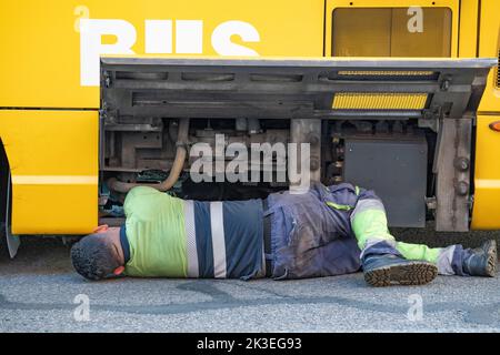 Machanic che lavora su un bus rotto con motore visibile Foto Stock