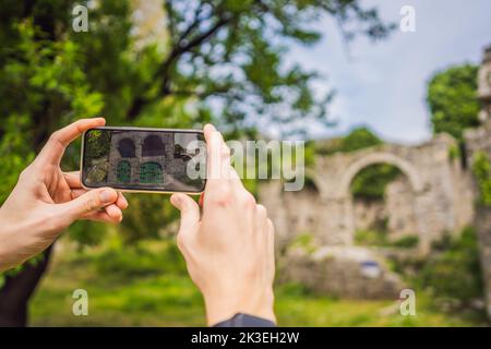 Concetto di realtà aumentata. Tenere in mano lo smartphone utilizzare l'applicazione AR per controllare le informazioni pertinenti sulla costruzione che era qui in tempi antichi Foto Stock