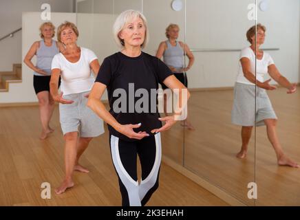 Le donne anziane che praticano la danza in studio sono in piedi nella prima posizione del balletto stand Foto Stock