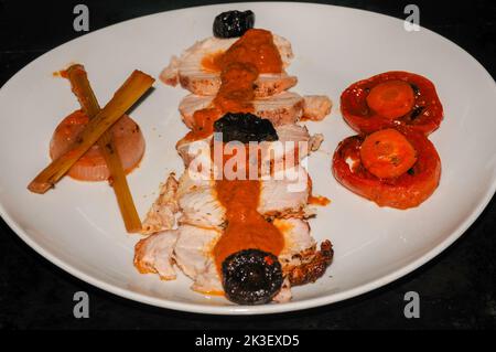 Costolette di maiale cucinate e servite su un piatto con pomodoro e cipolla guarnita Foto Stock