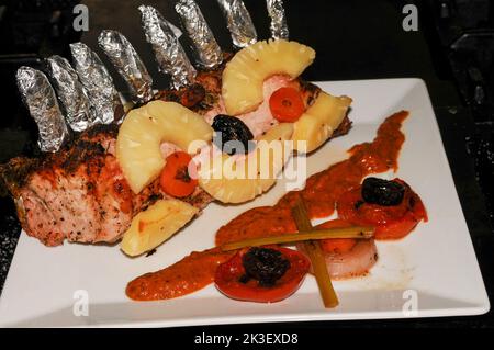Trita di maiale cucinata e servita su un piatto con pomodoro e cipolla guarnita Foto Stock