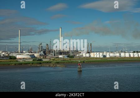 Anversa, Fiandre, Belgio - 10 luglio 2022: Industria lungo il fiume Scheldt. Raffineria di petrolio ExxonMobil con camini alti, circondata da stoccaggio ta Foto Stock