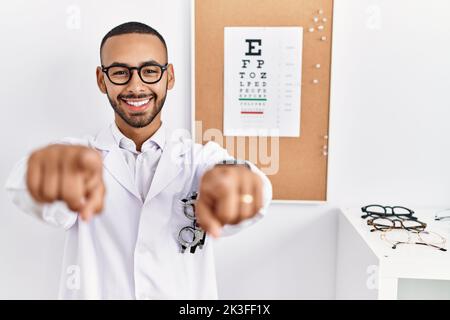 L'uomo ottico afro-americano in piedi dalla prova di vista che indica voi e la macchina fotografica con le dita, sorridente positivo e allegro Foto Stock
