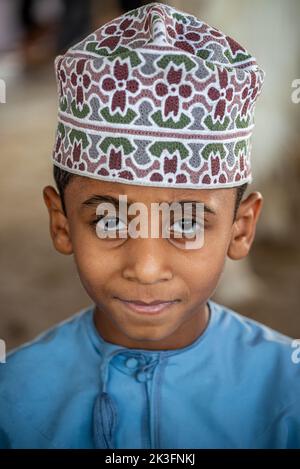 Ritratto di un giovane ragazzo con kuma (cappello tradizionale omani) al mercato del bestiame venerdì mattina, Nizwa, Oman Foto Stock