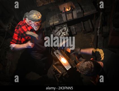 KRZEMIENICA, POLONIA. 25 settembre 2022. Krzysztof Panas (a sinistra) e Marcin Kosciak (a destra), due maestri fabbri locali della zona di Lancut, sono visti al lavoro durante una dimostrazione in un laboratorio tradizionale di fabbro a Krzemienica. Domenica 25 agosto 2022, nel villaggio di Krzemienica, nella contea di Lancut, Voivodato subcarpatico, Polonia. Credit: ASWphoto/Alamy Live News Foto Stock