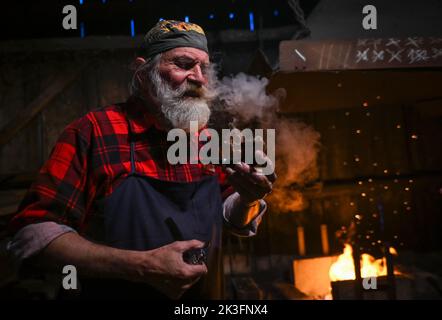 KRZEMIENICA, POLONIA. 25 settembre 2022. Krzysztof Panas, un maestro fabbro locale della zona di Lancut, sta facendo una pausa per fumare una pipa, durante una dimostrazione in un laboratorio tradizionale di fabbro a Krzemienica. Domenica 25 agosto 2022, nel villaggio di Krzemienica, nella contea di Lancut, Voivodato subcarpatico, Polonia. Credit: ASWphoto/Alamy Live News Foto Stock