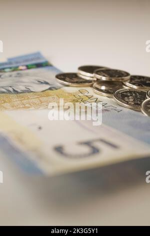 Banconota canadese da cinque dollari e monete su sfondo bianco. Foto Stock