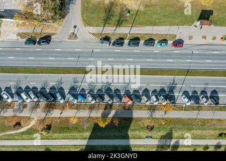 vista aerea dall'alto verso il basso delle auto parcheggiate su una strada urbana vuota il giorno di autunno soleggiato Foto Stock