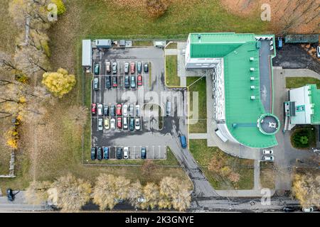 vista aerea dall'alto delle auto parcheggiate nei pressi di un piccolo edificio per uffici nella stagione autunnale Foto Stock