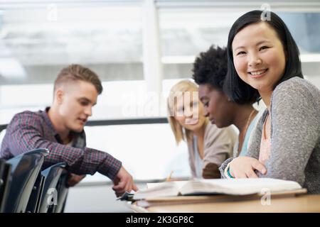 Un gruppo di studenti che si siedono in classe che seguono i compiti a casa. Foto Stock