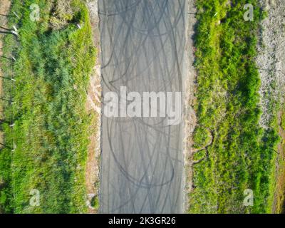 Vista aerea del contrassegno di slittamento che mostra i modelli di pneumatici in gomma e l'erba verde sul bordo della strada, Victoria, Australia. Foto Stock