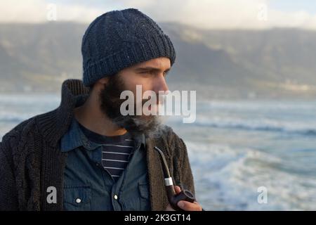 Fumare una pipa. Un uomo bearded che fuma una pipa fuori. Foto Stock