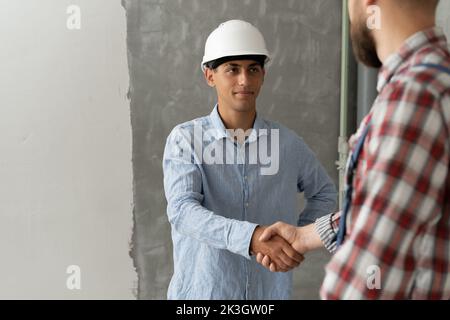 Appaltatore e cliente che scuotono le mani con il team builder nel sito di ristrutturazione. Partnership, concetto di appaltatore Foto Stock