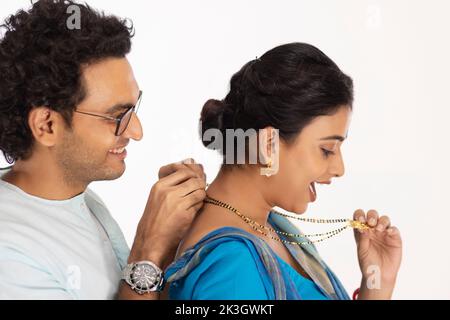 Marito amorevole che indossa mangalsutra a sua moglie Foto Stock