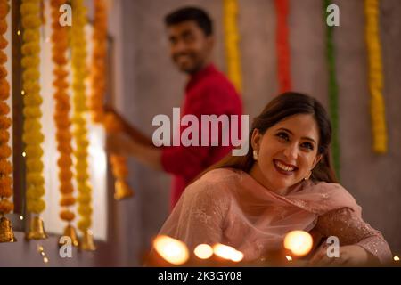 Donna decorazione ufficio mettendo diyas sul tavolo in occasione di Diwali Foto Stock