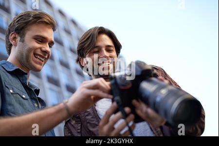 HES orgoglioso delle sue fotografie. Inquadratura a basso angolo di due uomini che guardano lo schermo lcd su una fotocamera digitale. Foto Stock