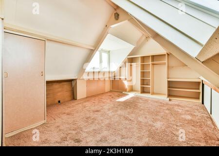 Una camera vuota accogliente e spaziosa in stile mansarda con una piccola finestra Foto Stock