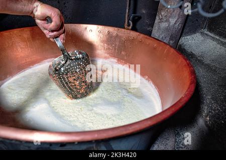 Il plucker di rame forato mescola la ricotta di pascoli montani del nord Italia Foto Stock
