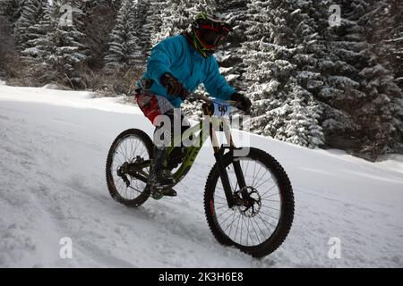 Sofia, Bulgaria - 22 gennaio 2022: Il ciclista percorre una discesa in bicicletta durante una gara estrema di mountain bike sulla neve sul monte Vitosha. Foto Stock