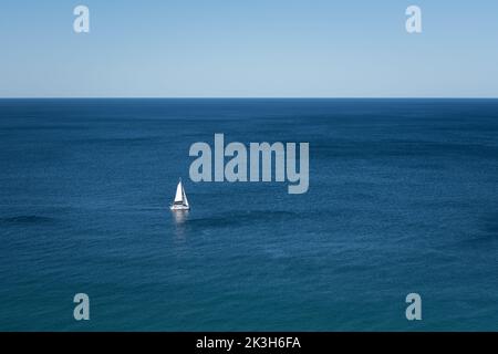 Barca a vela sull'oceano blu e cielo Foto Stock