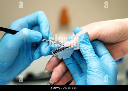 Costruzione di chiodi di bellezza. Prolunghe del chiodo inferiori. Master manicure in salone di bellezza aumenta le unghie allungando il cliente piastra unghie con acrilico o g Foto Stock