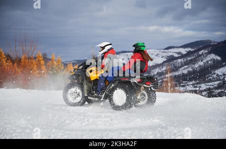 Ritratto di uomo e donna in sella a fuoristrada quattro ruote ATV. Concetto di attività ricreative e invernali. Foto Stock