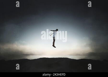 silhouette di un ragazzo felice che salta quasi toccando il cielo, concetto di libertà e di successo Foto Stock