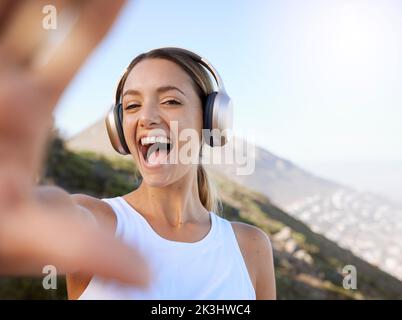 Fitness, musica con cuffie e donna selfie che si godono un tranquillo riposo di allenamento in montagna per il benessere. Ragazza benessere felice, eccitato e allegra fotografia Foto Stock