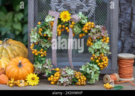 sistemazione con corona di bacche di girasole, fiori di ortensia e rami di scatola Foto Stock