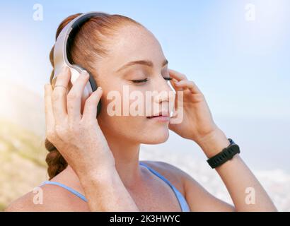 Donna, musica e podcast zen durante la meditazione in natura, relax e tranquillità con vista cielo blu. Radio, benessere e yoga da ragazza godendo una pausa con Foto Stock