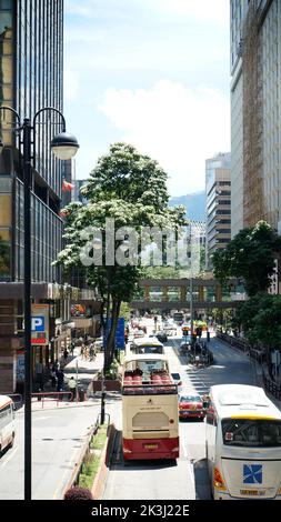 Uno scatto verticale di una strada a Hong Kong con traffico in una giornata di sole Foto Stock