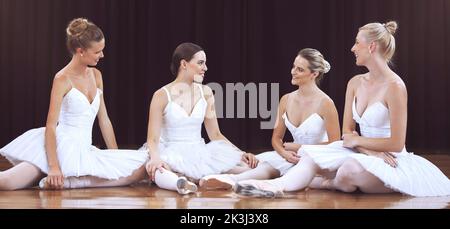 Balletto, arte e donne che riposano dopo un allenamento sul palco di un teatro per una performance classica. Danza creativa, elegante e ballerini seduti sul pavimento Foto Stock