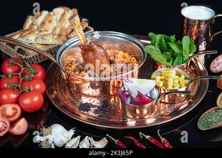 Tradizionale turco cibo gambo di agnello e riso. Gambo di agnello cotto lento. Gambo di agnello servito su un vassoio di rame e in una ciotola di rame. Foto Stock