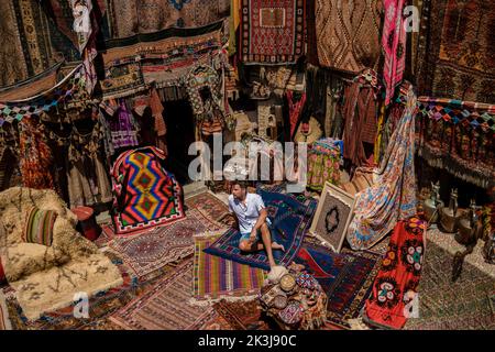 Giovane turista in un vecchio tradizionale negozio di tappeti turchi in casa grotta Cappadocia, Turchia Kapadokya. Tappezzeria colorata a Goreme Foto Stock