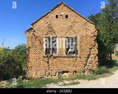 una casa di villaggio abbandonata circondata dal verde Foto Stock